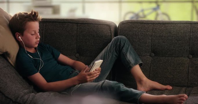 Boy is taking a smartphone from the couch