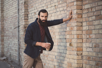 man leaning on brick wall