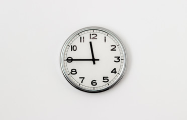 White Clock hanging on a white wall showing time 11:45