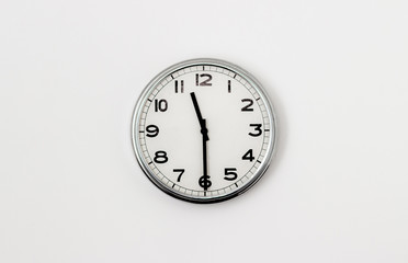 White Clock hanging on a white wall showing time 11:30