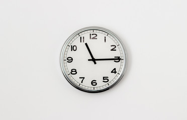 White Clock hanging on a white wall showing time 11:15