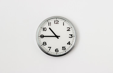 White Clock hanging on a white wall showing time 10:45