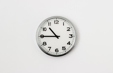 White Clock hanging on a white wall showing time 10:45