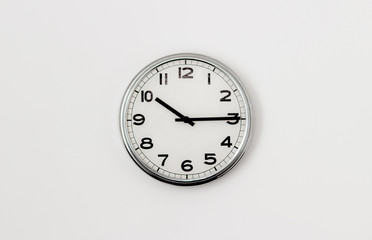 White Clock hanging on a white wall showing time 10:15
