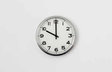 White Clock hanging on a white wall showing time 10:00