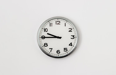 White Clock hanging on a white wall showing time 9:45
