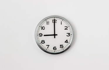 White Clock hanging on a white wall showing time 9:00