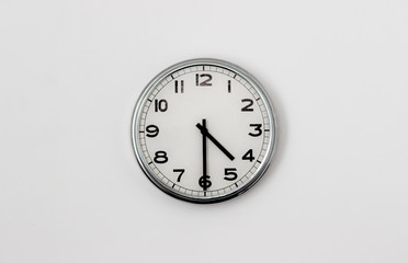 White Clock hanging on a white wall showing time 4:30
