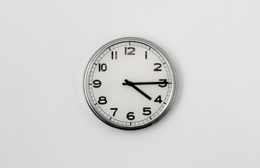 White Clock hanging on a white wall showing time 4:15