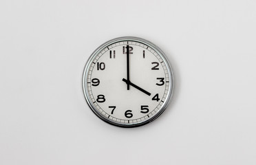 White Clock hanging on a white wall showing time 4:00