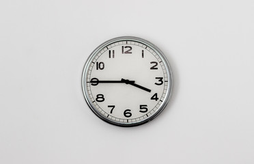 White Clock hanging on a white wall showing time 3:45