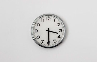 White Clock hanging on a white wall showing time 3:30