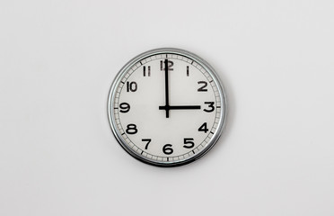White Clock hanging on a white wall showing time 3:00