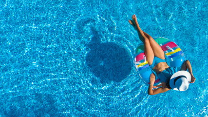 Aerial top view of beautiful girl in swimming pool from above, relax swim on inflatable ring donut...