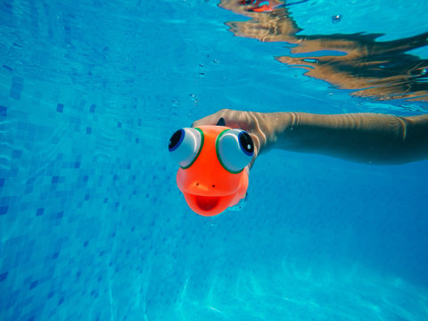 Child Playing With Generic Rubber Fish Toy In Swimming Pool