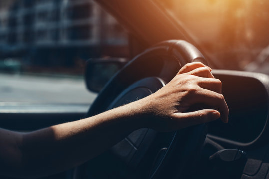 Female hand on car steering wheel
