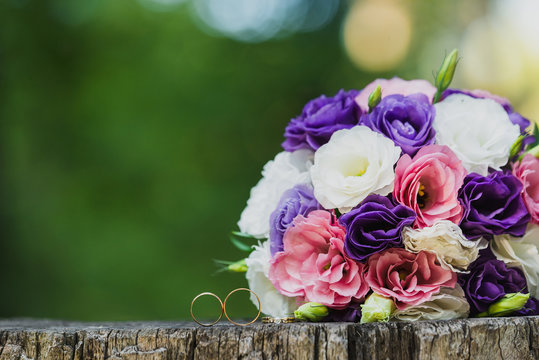 wedding rings and bouquet on the wooden surface