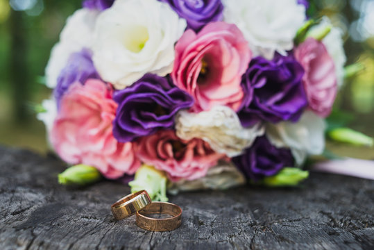 wedding rings and bouquet on the wooden surface