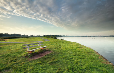 bench on green grass by big lake