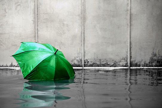 Green umbrella floating concept. Flooded on street. .Waiting for help me after the rain. Black and white colors. Close up.