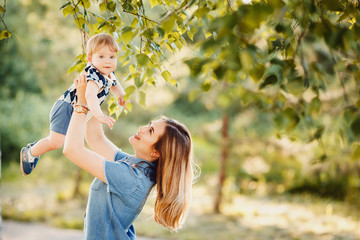 Naklejka premium Mom and little son are playing in the park. The boy smiles, laughs. Concept Mother's Day.