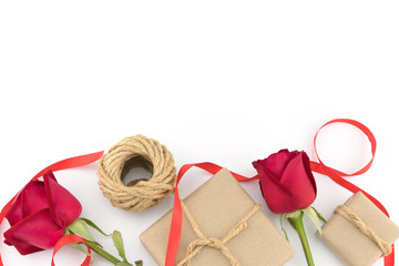 Brown gift boxes, ropes and red ribbon decorated with red roses on white background with copy space