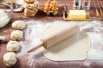 Rolled out dough on wooden table with rolling pin