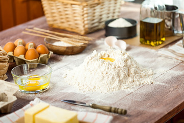 Egg yolk in flour on a wooden table in a bakery. Rural or rustic style.