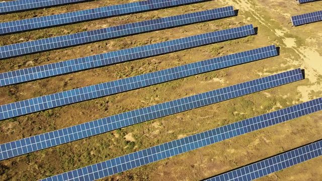 Aerial View. Flying over the solar power plant with sun. Solar panels and sun. Aerial drone shot. 4K 30fps