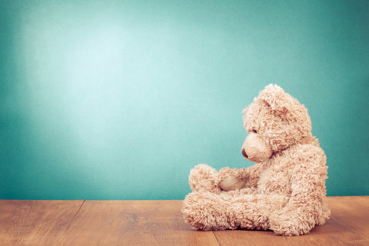 Teddy Bear retro old toy siting alone front mint green background. Vintage style filtered photo