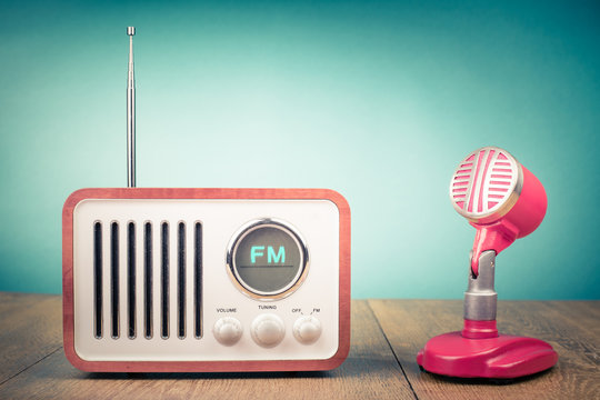 Retro wooden FM radio receiver, old microphone from 60s on table. Vintage style filtered photo
