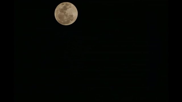 4K time lapse movie of Super Full Moon passes fast across black night sky.