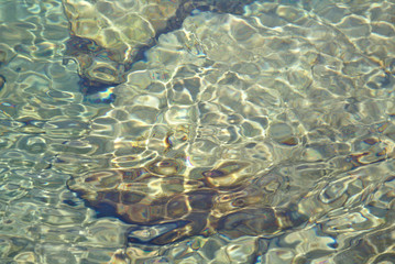 Shallow water over rocky bottom with reflections and small waves