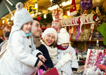 Obraz premium Happy family choosing Christmas decoration at Christmas market