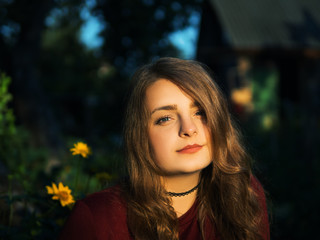 Fototapeta premium the girl in the garden next to the yellow flowers daisies at sunset in the summer