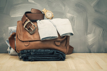 Asian vintage style men clothing and jeans and bag put on wooden table and loft concrete wall texture background.