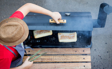 The chef in the hat bakes a Panini in the oven on the coals