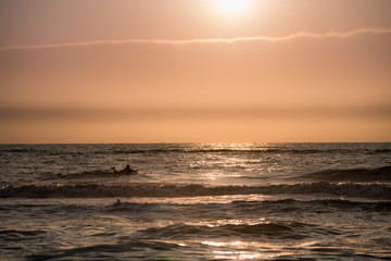 Obraz premium Surfing with the bright orange sun setting 2