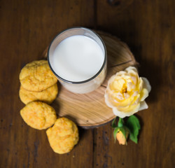 carrot cookies, glass of milk on the old wooden background with rose flower
