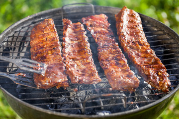 american barbecue - preparing bbq ribs on charcoal grill