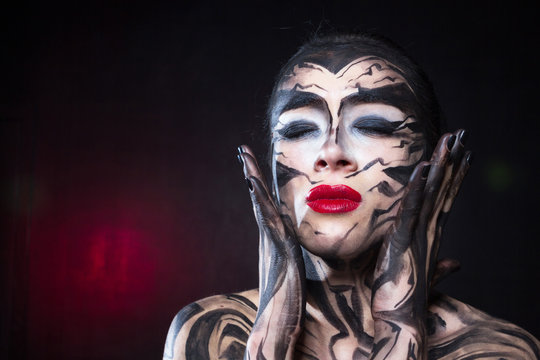A painted woman with black paint is experiencing emotions.