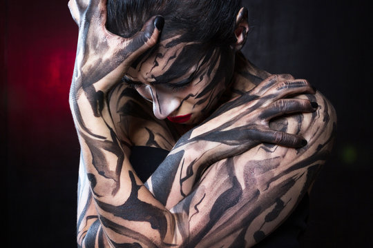 The painted woman with black paint tightly closes her hands and digs her fingers into the skin.