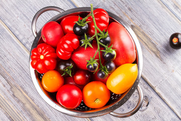 Various colorful tomatoes. Red, yellow, orange and black tomatoes on wooden background. View from above, top studio shot