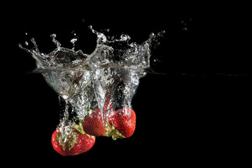 Strawberries splashing into water