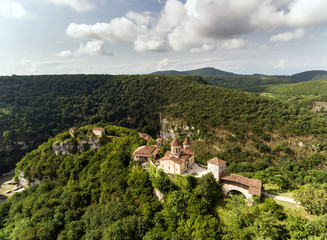 Fototapeta na wymiar AERIAL. Old monastery hiding in the forests, also known as Motsameta, Georgia