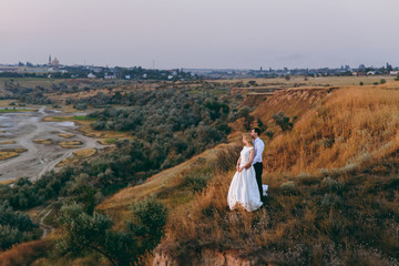Fototapeta na wymiar Bride and groom are walking together at sunset near the sea