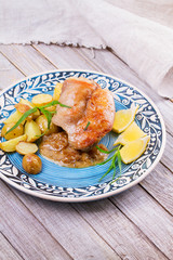 Rabbit with potatoes, lemon and tarragon on blue plate