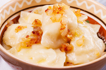 Varenyky, vareniki, pierogi, pyrohy or dumplings, filled with potato and served with salty caramelized onion