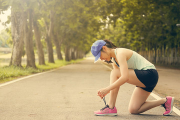 Sport runner girl tie shoes before running in the park.