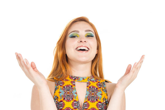 Girl laughs and gestures with her hands. Redheaded girl wearing colorful yellow dress. Summer..